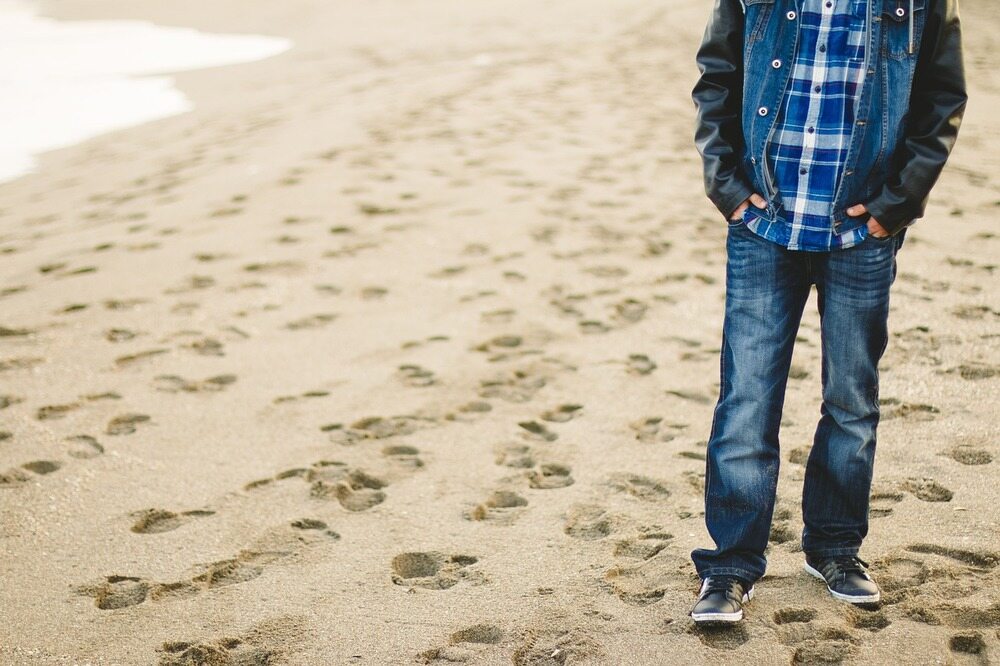 Mann mit Jeans beim Strandspaziergang