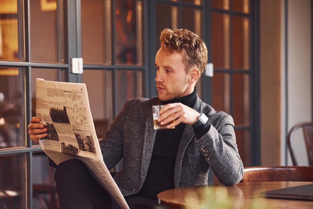 Mann liest Zeitung im Cafe